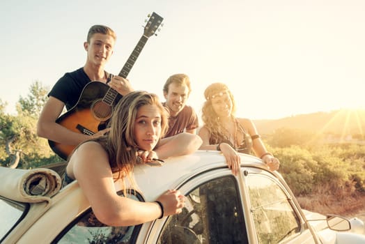 Group of happy people in a car at sunset in summer.
