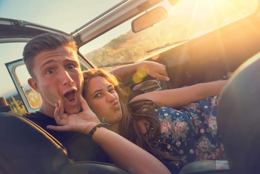 Happy couple in a car enjoying sunset.