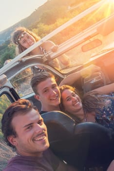 Group of happy people in a car at sunset in summer.