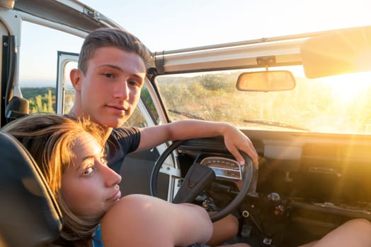 Happy couple in a car enjoying sunset.