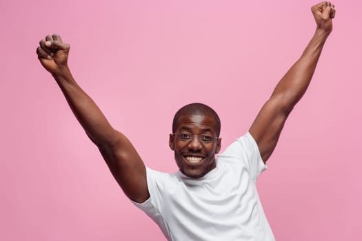Portrait of a very happy afro american man showing emotions in studio on pink background