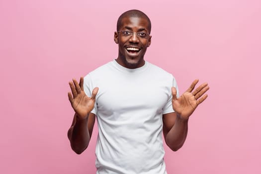 Portrait of a very happy afro american man showing emotions in studio on pink background