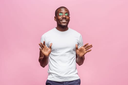 Portrait of a very happy afro american man showing emotions in studio on pink background