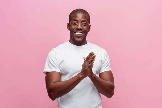 Portrait of a very happy afro american man showing emotions in studio on pink background