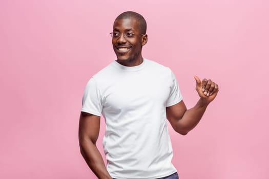 Portrait of a very happy afro american man showing thumbs up in studio on pink background