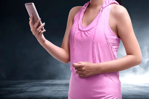 Close-up of asian sporty woman using mobile phone on the room with concrete floor