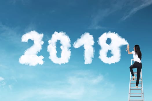 Business woman using stair spraying white cloud with 2018 shape on the sky