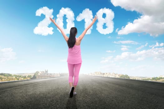 Happy asian runner woman looking 2018 number from clouds at sky. Happy New Year 2018