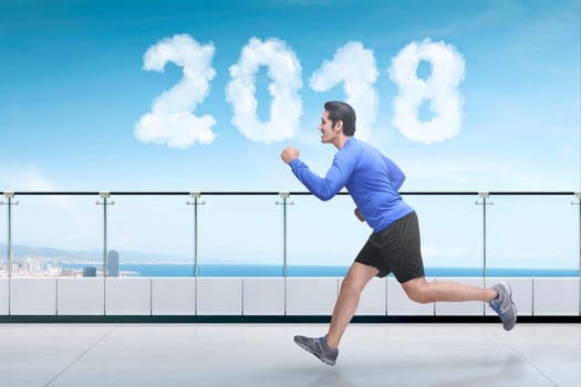 Handsome asian man running on building balcony with cloud shaped 2018 at sky. Happy New Year 2018