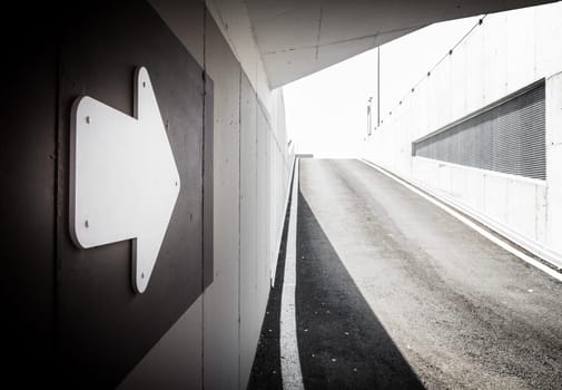 Underground parking garage exit with arrow signal. Space for text.