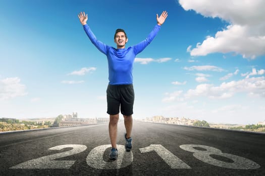 Young asian man running with 2018 number on asphalt road. Happy New Year 2018