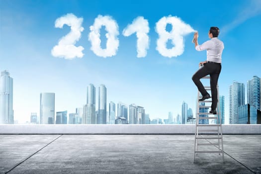 Businessman using stair spraying white cloud with 2018 shape on the building rooftop