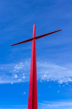 Large red christian cross on sky background. Passion symbology. Easter.