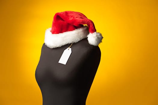 The empty dummy with Santa hat, sale price tag hanging from the button hole. The shopping and sale concept
