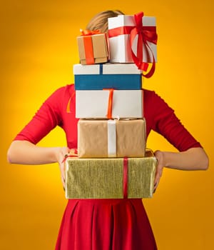 The closeup picture of woman's hands with gift boxes on yellow background