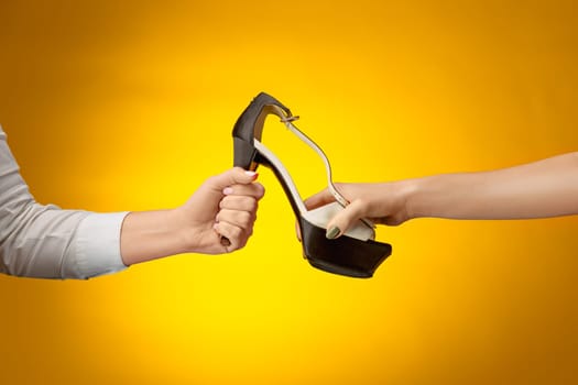 The female shoe with female and male on hands on yellow paper. Shopping and black friday concept