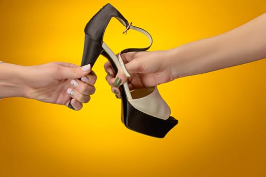 The female shoe with female and male on hands on yellow paper. Shopping and black friday concept