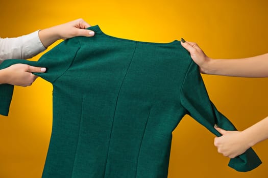 Textile, design, clothing, fashion concept. The female hands with dresses in her hands on yellow. Black friday and sale concept