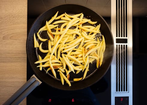 Fry noodles in a cast iron pan on induction cooker with cooker