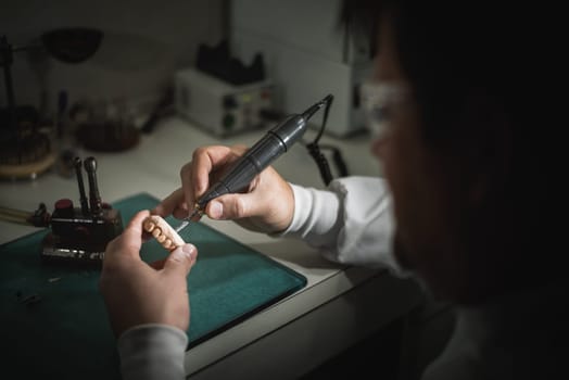 Dental prosthesis, artificial tooth, prosthetic, hands working on the denture, false teeth.