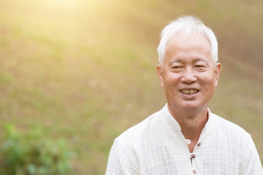Happy Asian old man relaxing at outdoor park.
