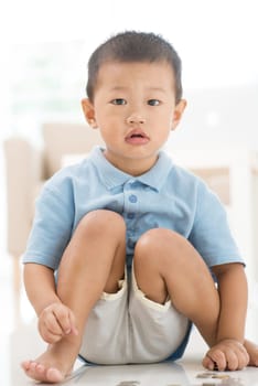 Asian young boy saving coins at home. Child future educational fund concept.