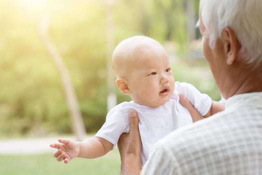 Baby grandchild and grandfather having fun outdoors. Asian family, life insurance concept.