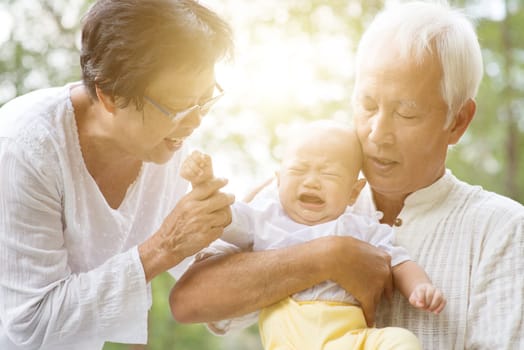 Grandchild and grandparents having fun outdoors. Asian family, life insurance concept.