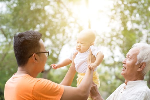 Happy grandfather, father and baby grandson at outdoors park. Asian multi generations family.
