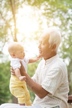 Baby grandchild and grandfather. Asian family having fun outdoors.
