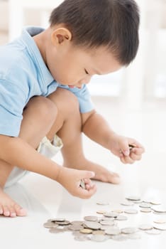 Asian boy saving money at home. Child education fund concept.