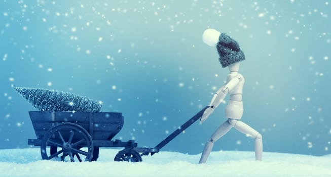 Wooden puppet with an old wooden cart deliver a Christmas tree