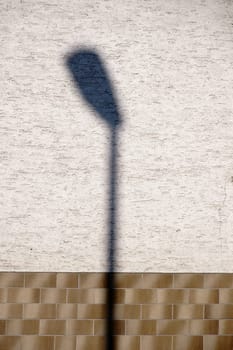 A lantern shadow on a plastered and clinkered façade.