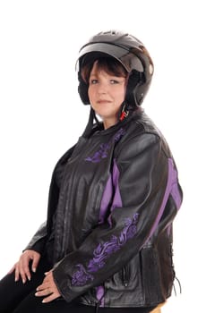 A forties years old woman in a leather jacket and motorcycle helmet.sitting on a chair looking into the camera, isolated for white background.