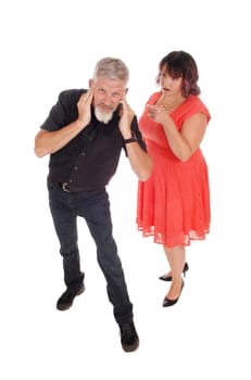 A full sized woman in a red dress is shouting at her husband, he is.covering his ears, isolated for white background.