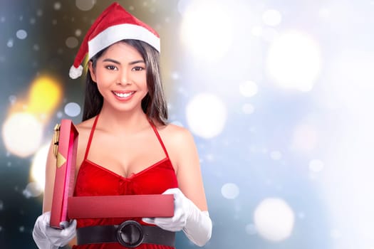 Beautiful asian girl with santa's hat opening christmas gift against blurred background