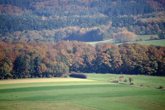 Wooded mountain ridges with mixed forest and coniferous forest and meadows in the valley.