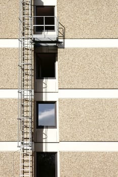 A fire ladder on the side of a residential building casts a shadow.
