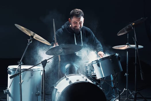 Drummer rehearsing on drums before rock concert. Man recording music on drum set in studio with show effect in the form of flour