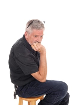 A gray hared middle aged man sitting isolated for white background with.his hand on chin and glasses on his head, isolated for white background..