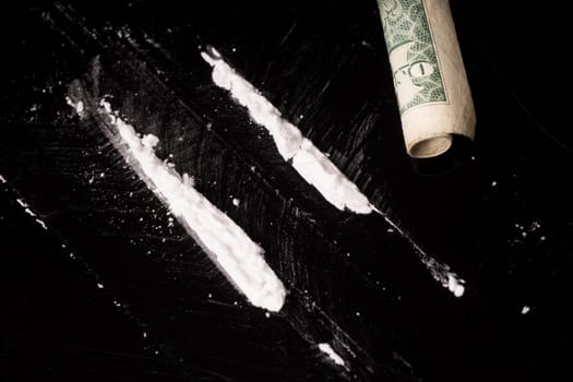 cocaine or other illegal drugs that are sniffed by means of a tube, isolated on black glossy background
