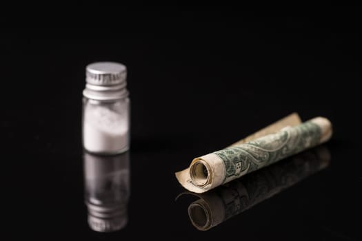 cocaine or other illegal drugs that are sniffed by means of a tube, isolated on black glossy background