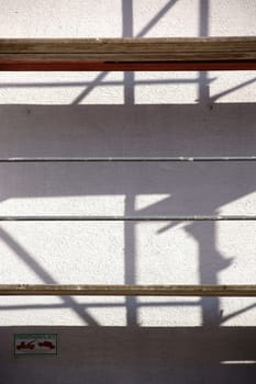 The pipes and wooden inserts of a scaffolding cast abstract shadows on a wall.