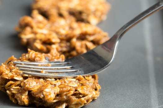 Fork pressing down raw oatmeal cookie dough on baking sheet