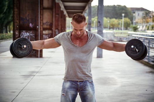 Attractive Muscular Hunk Man Lifting Weights Outdoor, Looking Down for the Effort