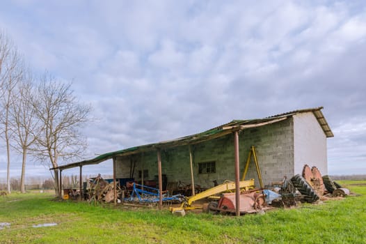 old shelter for agricultural tools, with trees in the background