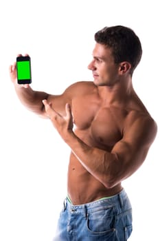 Shirtless handsome man with a muscular athletic body pointing to his mobile phone while displaying the blank green screen