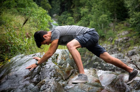 Side View of Young Man Clambering Over Rocky Terrain in the Mountain