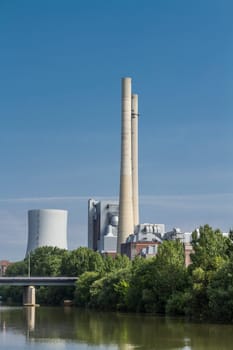 german coal-fired power station at the river Neckar with blue sky and bridge.