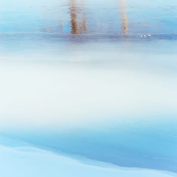 Abstract image of a tree reflecting on blue and white ice.